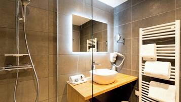 A modern bathroom with a glass shower enclosure, a wooden vanity, a large mirror, and a towel rack.