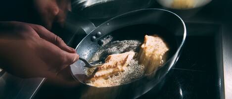 Una persona cocinando en una sartén sobre la hornilla.