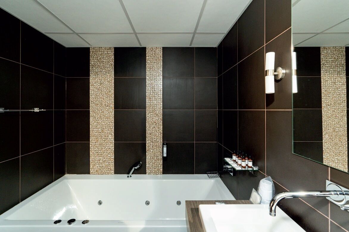 Un baño moderno con una bañera grande, una zona de lavamanos separada y un espejo.