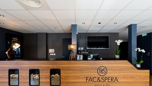 Un comptoir d’accueil d’hôtel avec un revêtement en bois, un téléviseur fixé au mur et trois photos encadrées.
