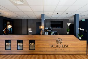 Un mostrador de recepción de hotel con detalles de madera, un televisor integrado y tres fotografías enmarcadas.