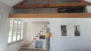 Una escalera con escalones de madera y techo inclinado con vigas a la vista.