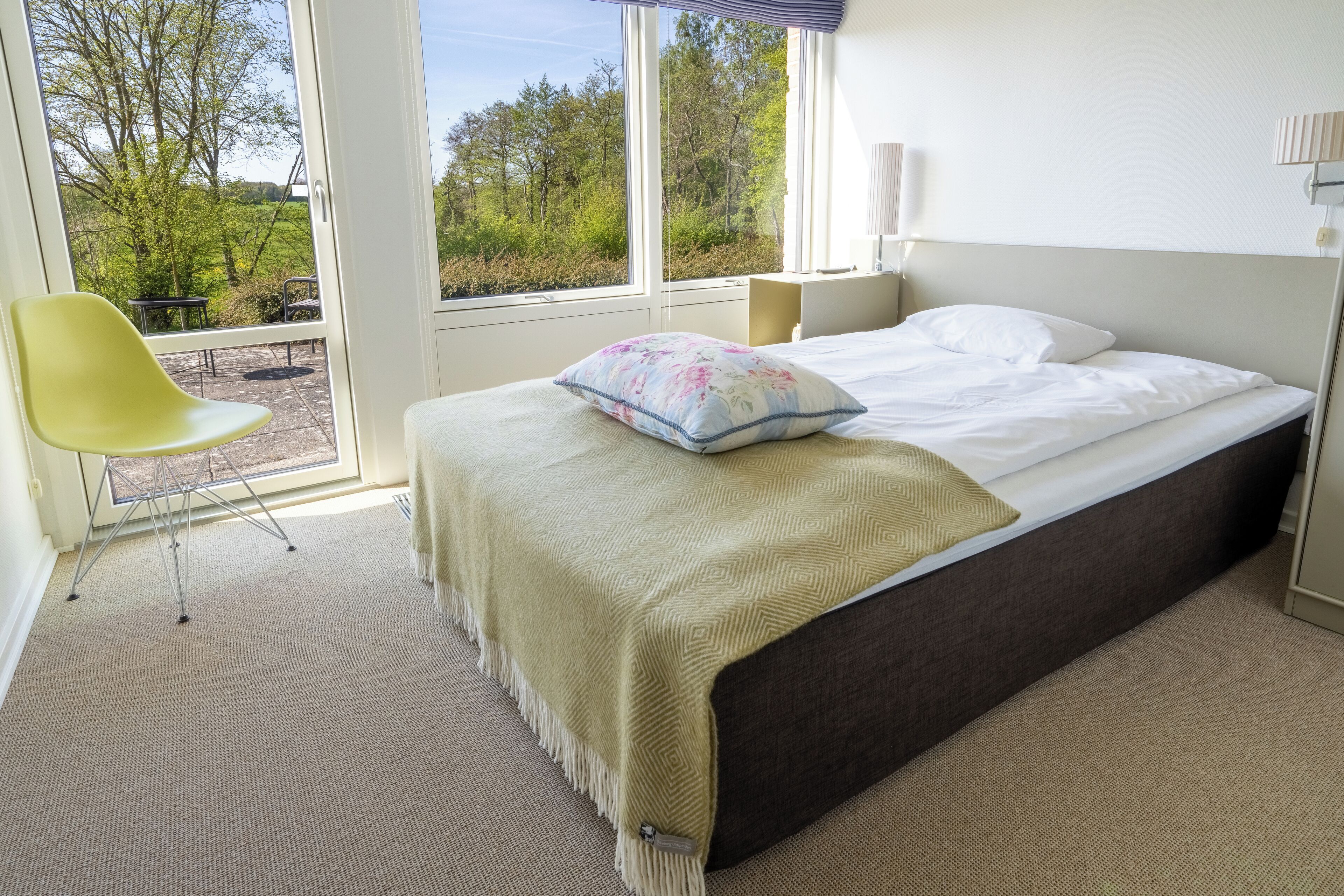 Un dormitorio con cama, una silla y vistas al exterior.