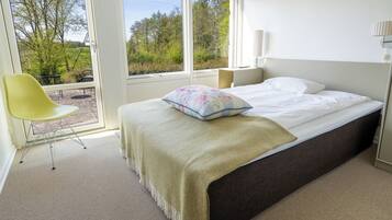 Un dormitorio con cama, una silla y vistas al exterior.