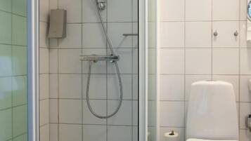 Une salle de bain moderne avec une douche à parois de verre, des toilettes et une petite poubelle.