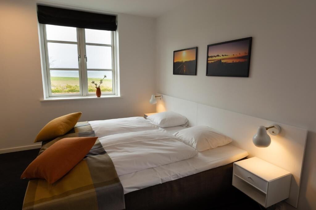 A bedroom with a bed, bedside tables, a window with a view, and wall-mounted artwork.