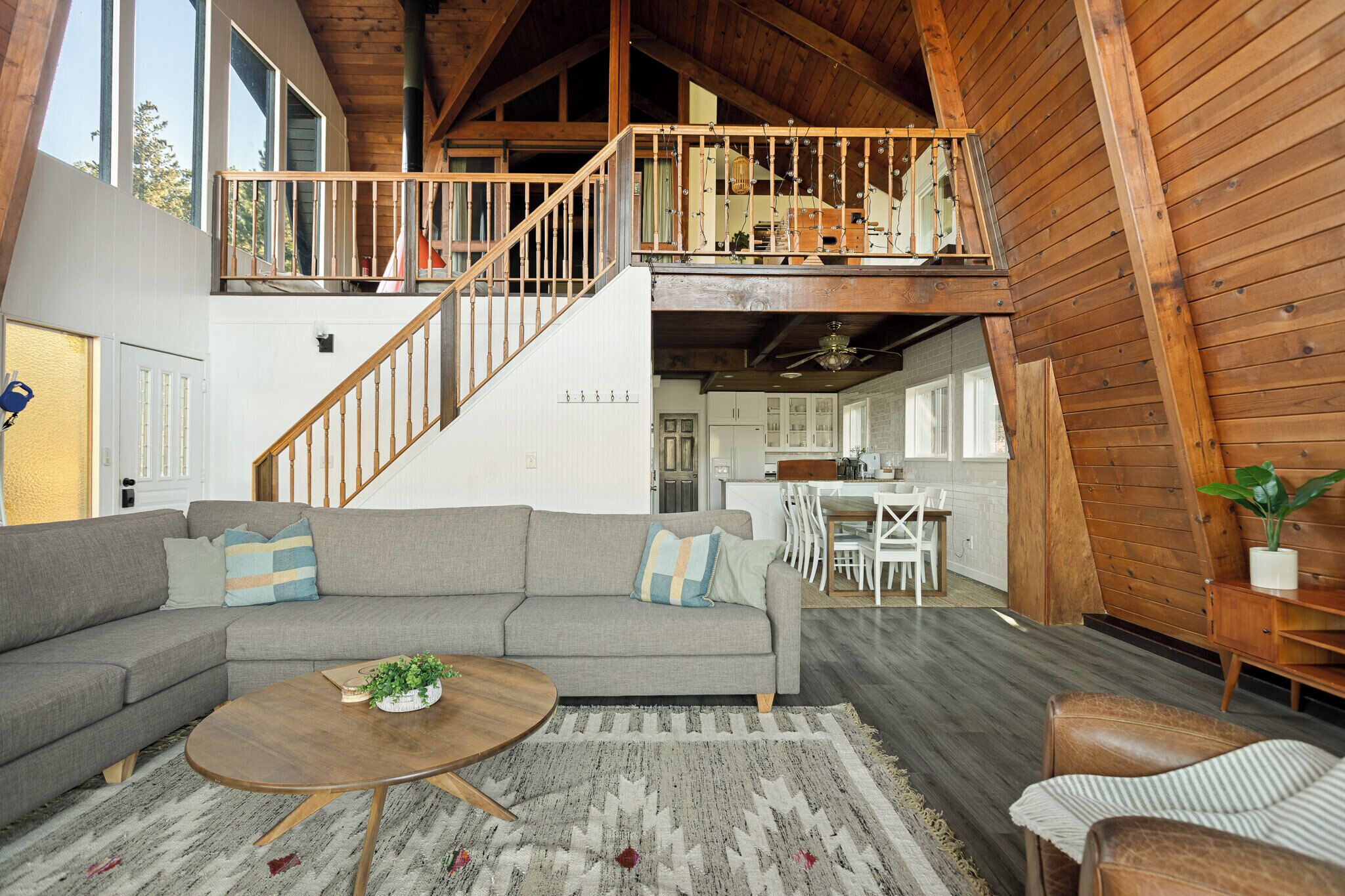 A spacious living area with a large gray sectional sofa, a wooden coffee table, and a staircase leading to an upper level.