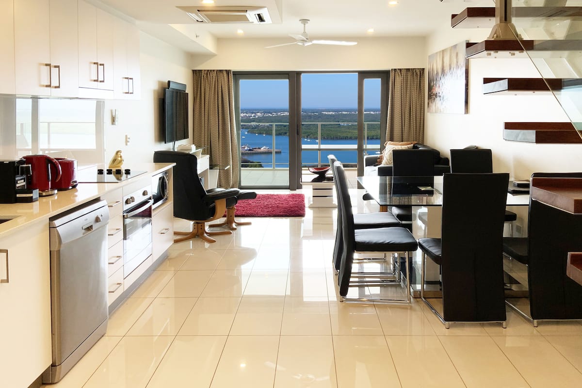 A modern kitchen with a dishwasher, stove, and a dining area with a table and chairs.