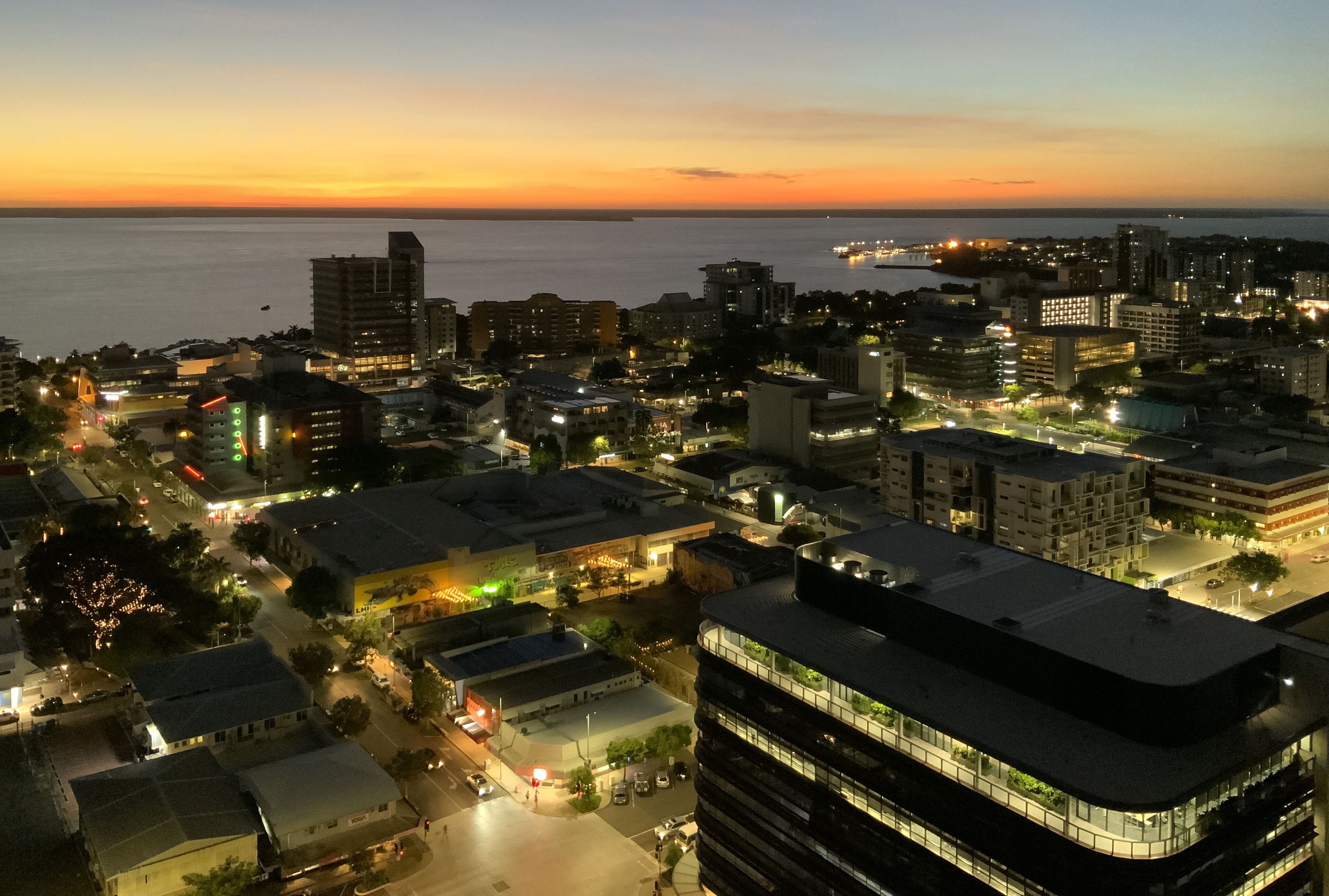 A cityscape at dusk with buildings and streets illuminated.