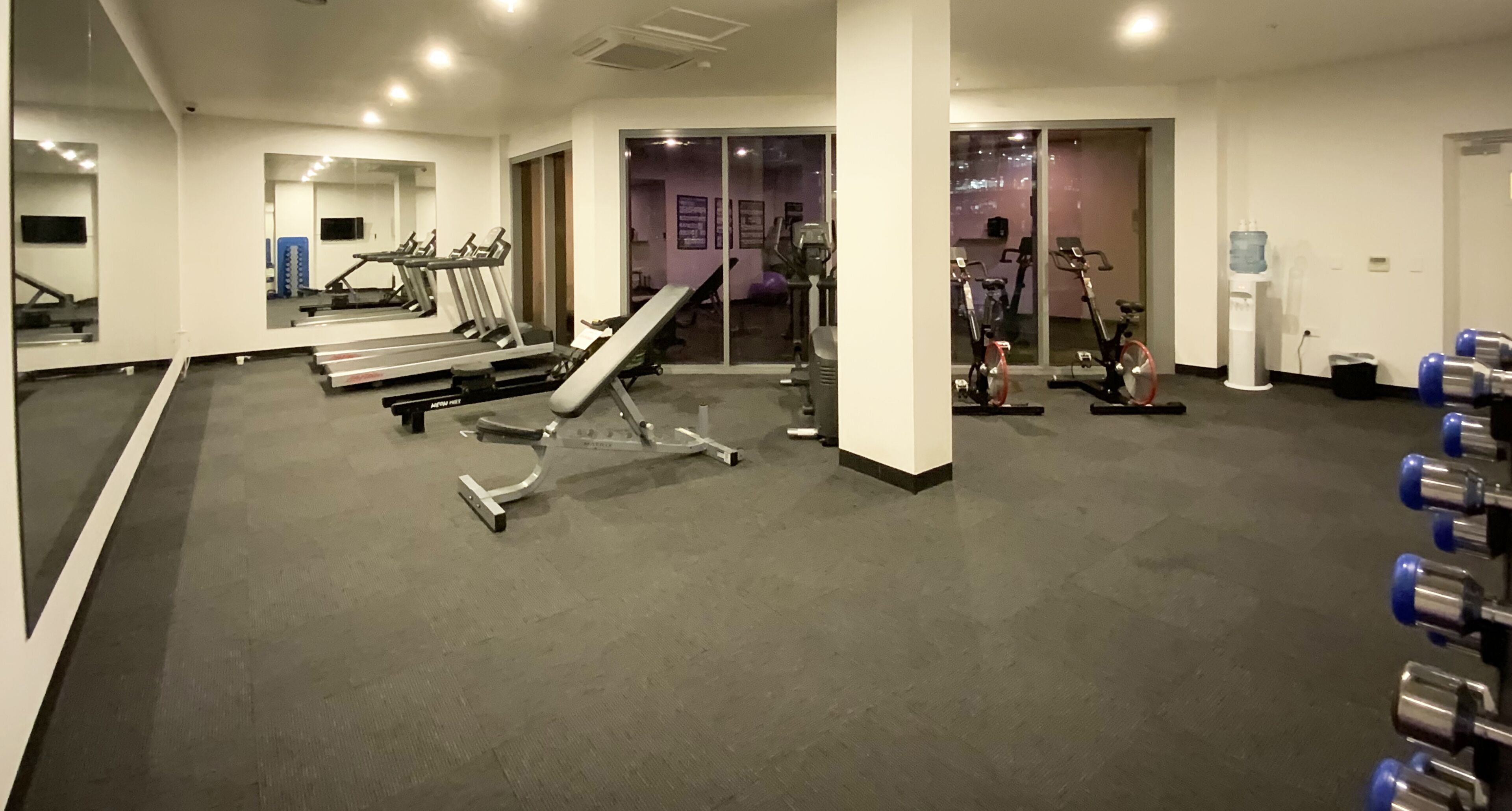 A gym with exercise equipment, including treadmills, a rowing machine, and stationary bikes.