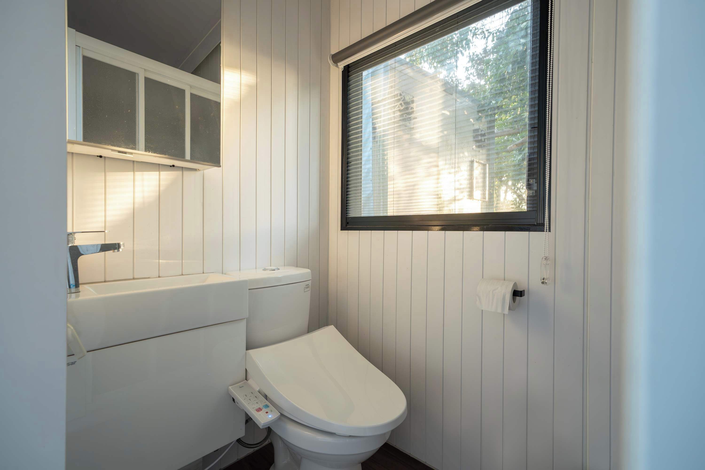 Ein kleines, sauberes Badezimmer mit Toilette, Waschbecken und Fenster.