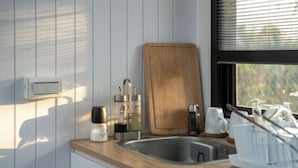 Eine Küche mit Schneidebrett aus Holz, Edelstahlspüle und diversen Küchenutensilien.