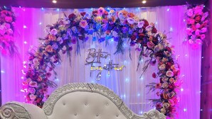 Um sofá branco com detalhes ornamentais, posicionado em frente a um painel floral com a frase “Better Together” e um símbolo de coração.