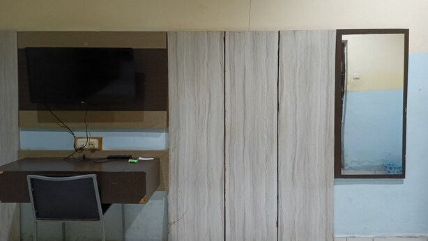 A room with a desk, a television mounted on the wall, and a window with a view of the outside. - Hotel O Karunia Kost & PenginapanNearSiring Marabahan (Ulek Barito) (Marabahan)