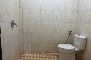 Un baño con inodoro, ducha y suelo de baldosas.