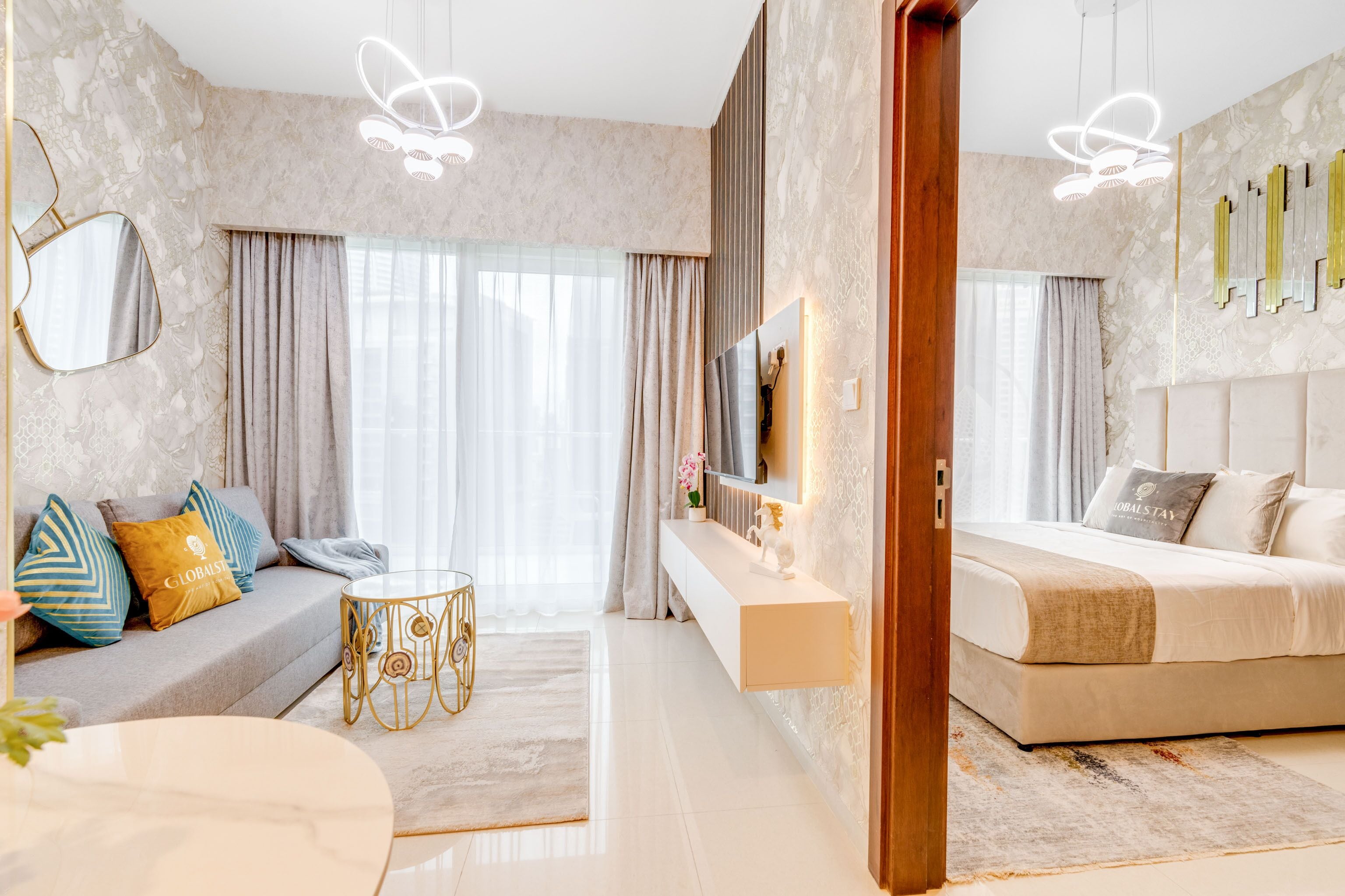 Moderni hotellihuone, jossa on sohva, sänky, televisio ja pieni pöytä.
