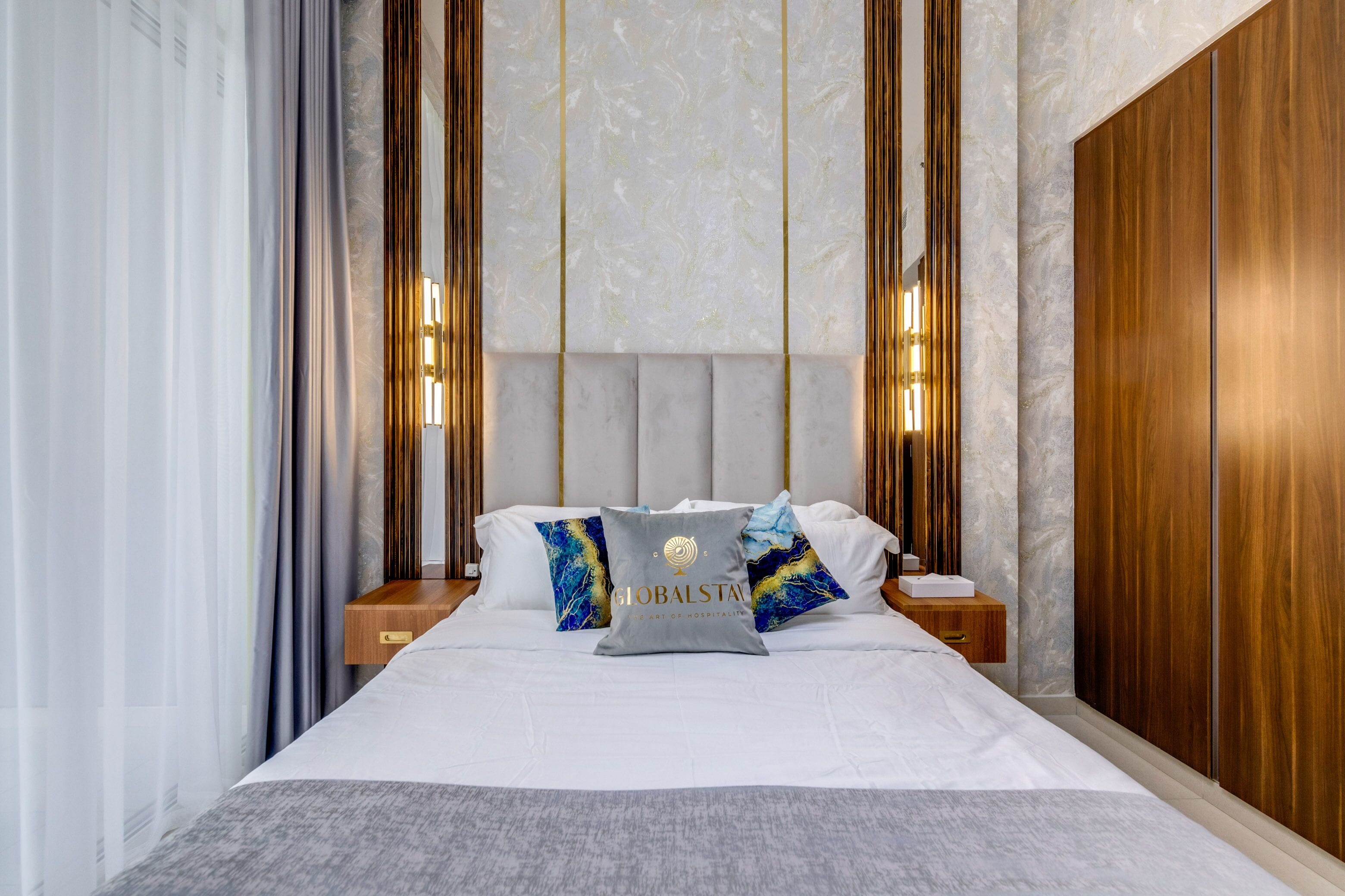 Una habitación de hotel moderna con una cama grande, cabecera de madera y dos mesitas de noche.