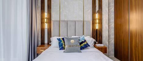 Una habitación de hotel moderna con una cama grande, cabecera de madera y dos mesitas de noche.