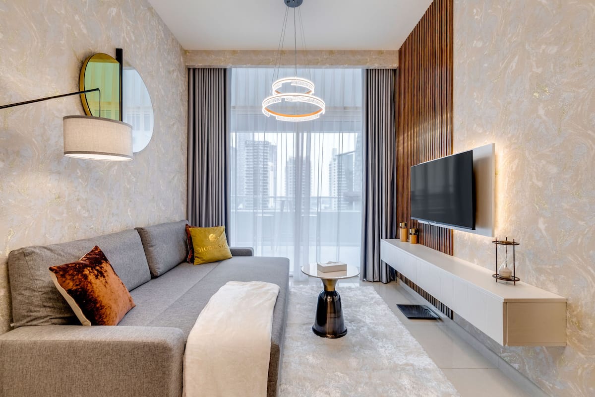 A modern living room with a sofa, a coffee table, a TV, and a large window with curtains.