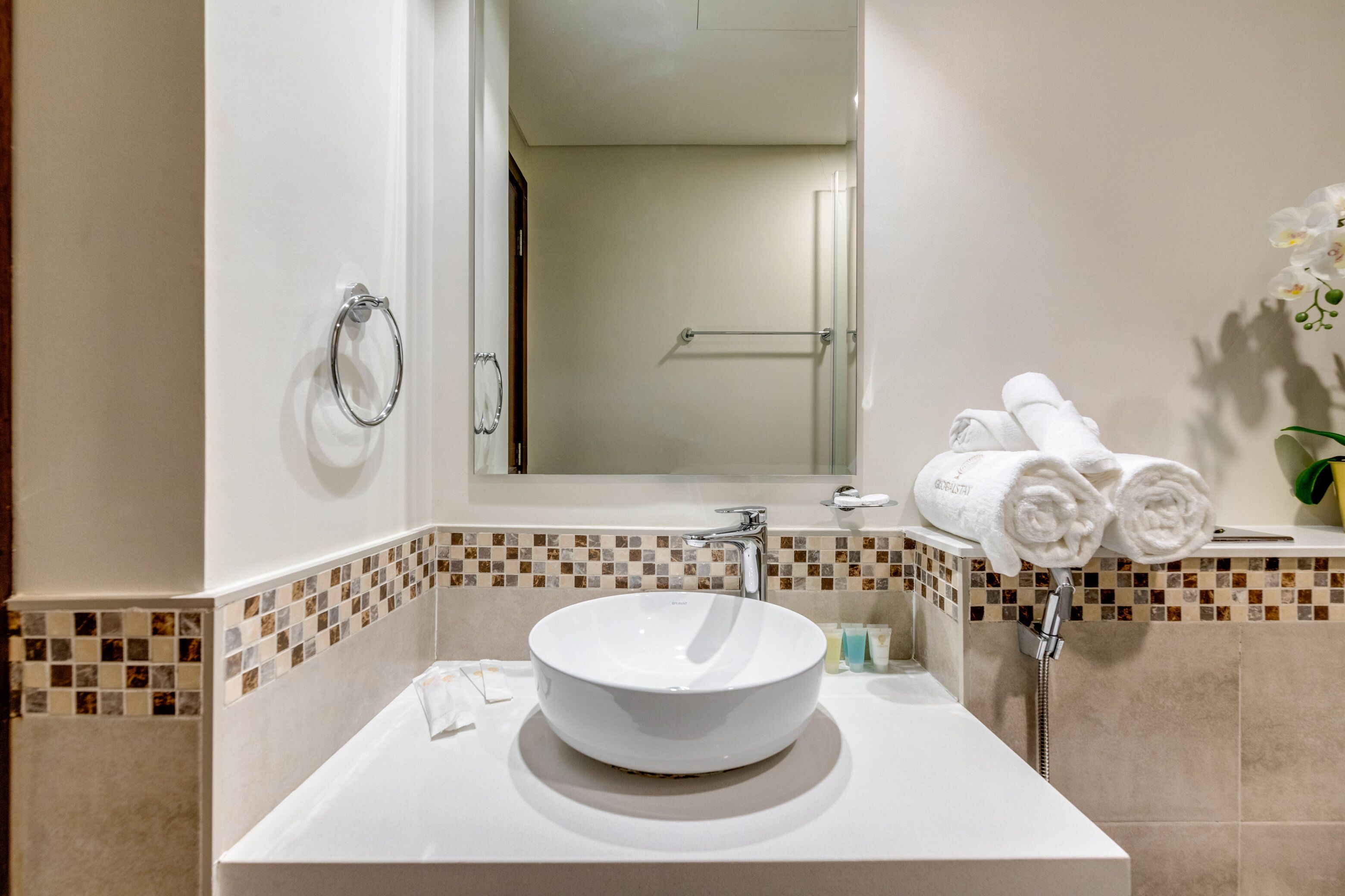 A bathroom with a white sink, a mirror, a towel rack, and a shower area.