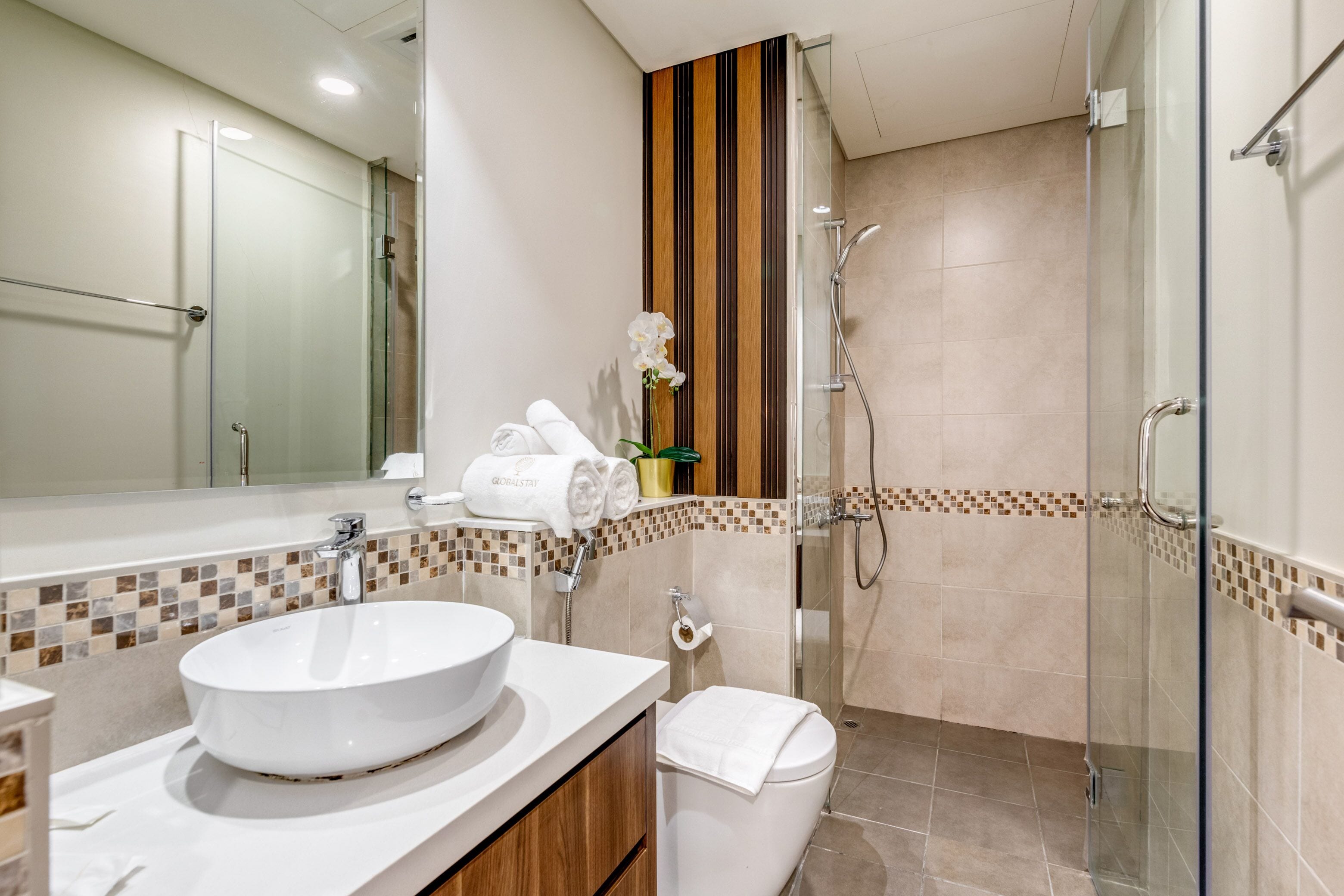 Une salle de bain moderne avec une douche à parois de verre, un lavabo blanc et des toilettes.