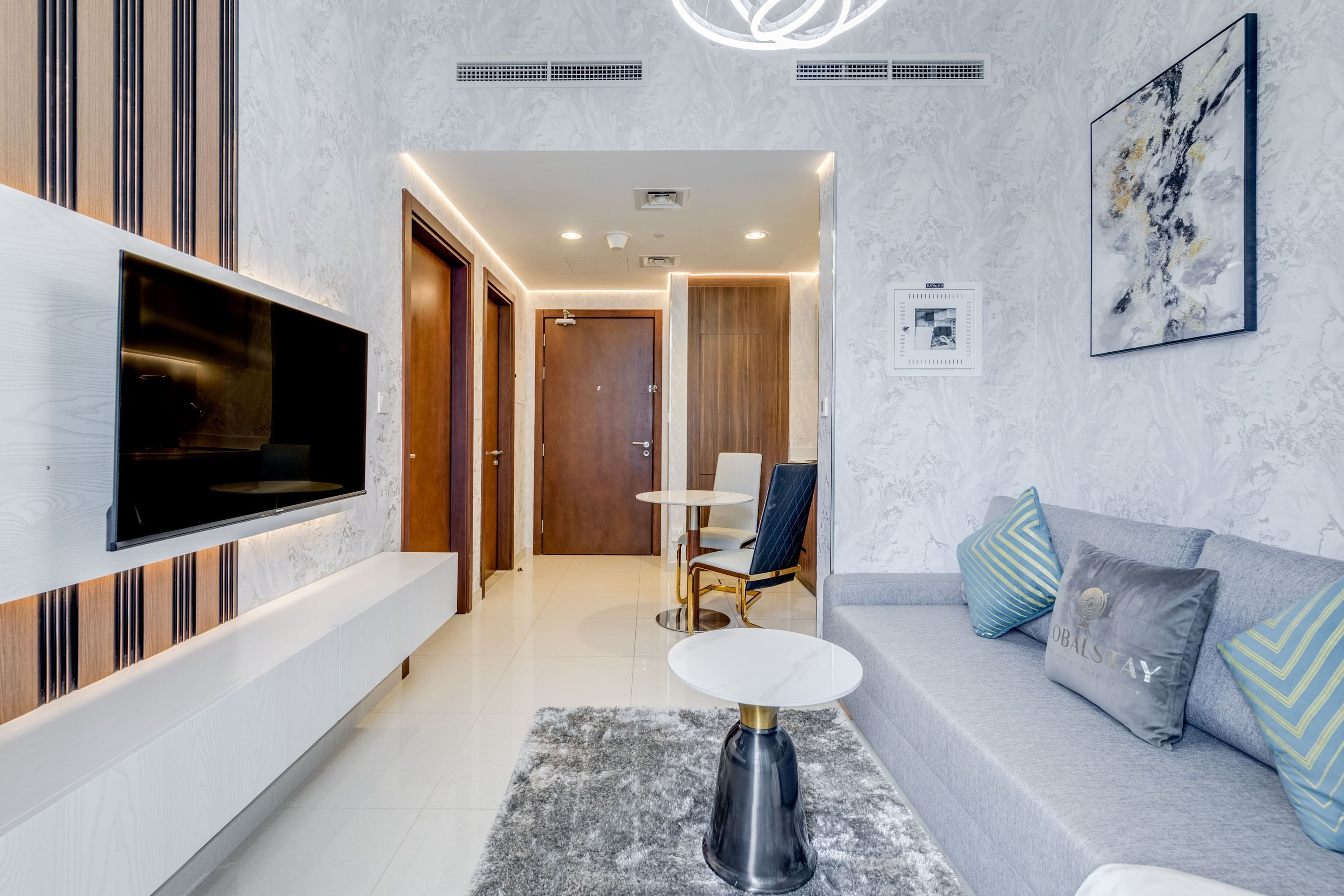 A modern living room with a flat-screen TV, a sofa, a coffee table, and a dining area with a table and chairs.