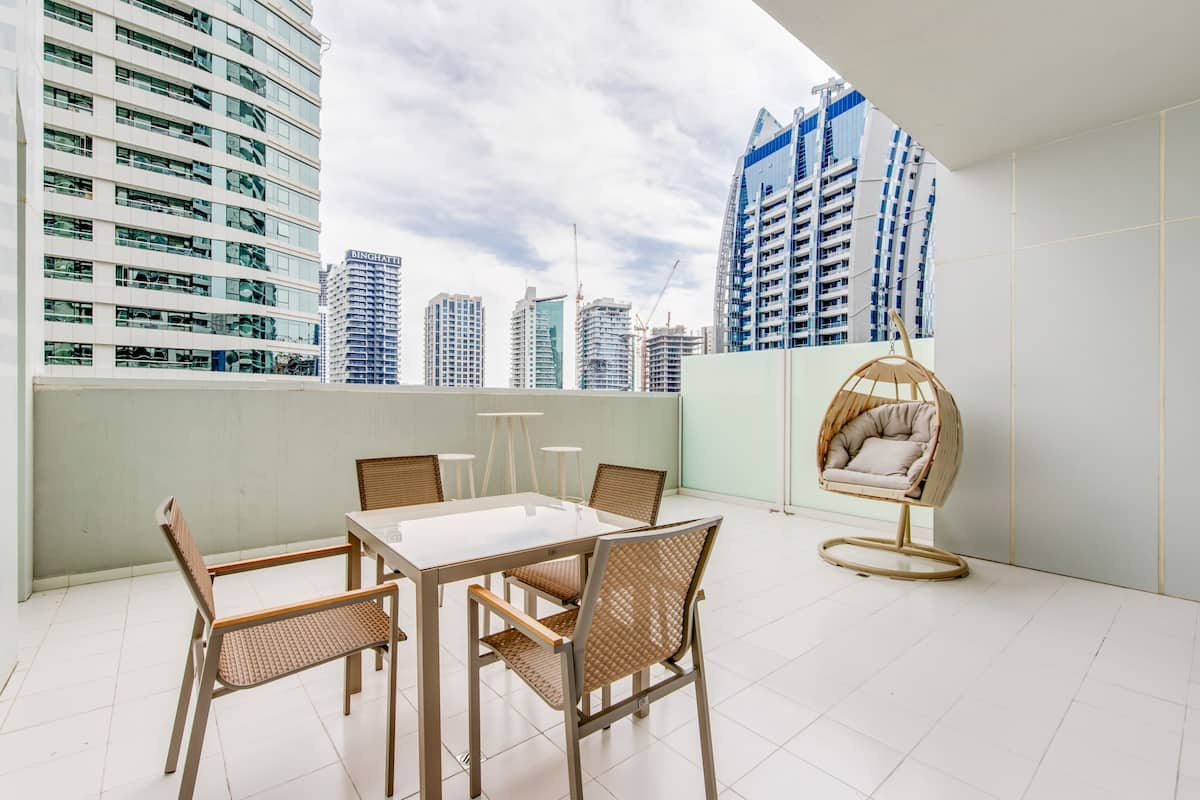 A rooftop terrace with a dining table, chairs, and a hanging chair.