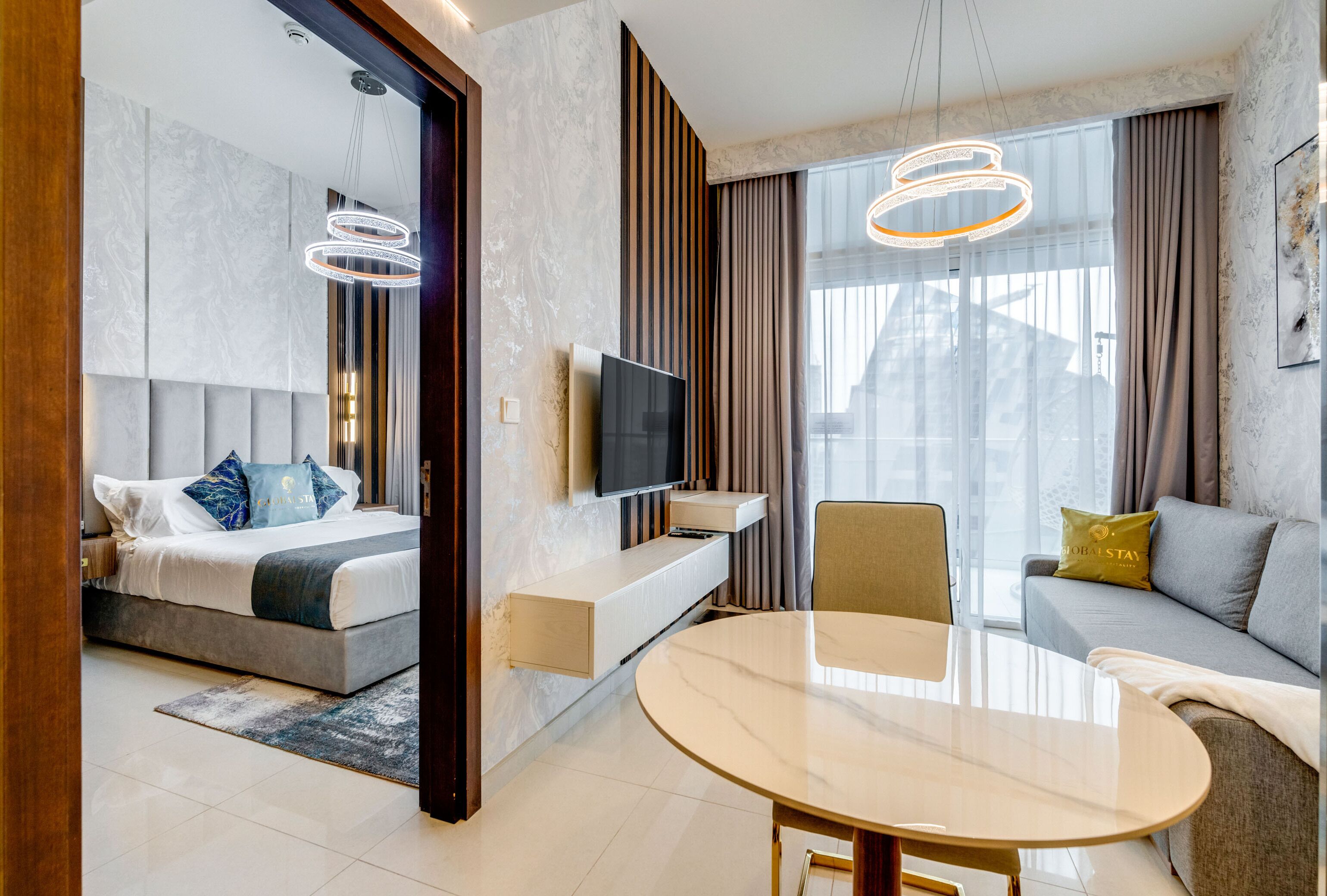 A modern hotel room with a bed, a TV, a dining table, and a sofa.