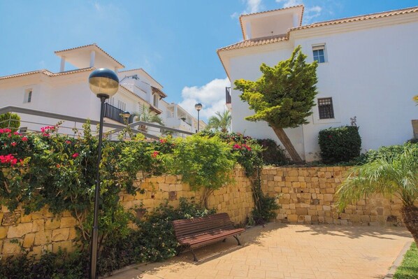 Un patio empedrado con un banco, un muro de piedra y un árbol.