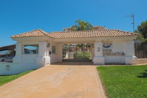 A gated entrance with a tiled roof, a sign reading 'Vista Hermosa,' and a paved pathway leading to the gate.