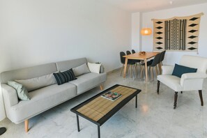 A modern living room with a sofa, coffee table, dining table, and chairs. - Wonderful, bright, spacious apartment & pool (Benalmádena)