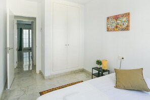 A bedroom with a bed, a wardrobe, a nightstand with a lamp, and a wall-mounted globe.