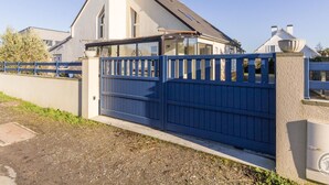 A modern house with a blue gate, a concrete wall, and a clear sky. - Family House in Montmartin-sur-Mer (Montmartin-sur-Mer)