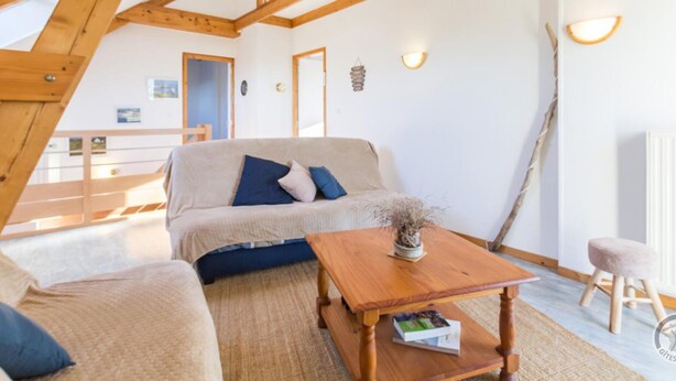 A cozy living room with a wooden ceiling, a sofa, a coffee table, and a small stool. - Family House in Montmartin-sur-Mer (Montmartin-sur-Mer)