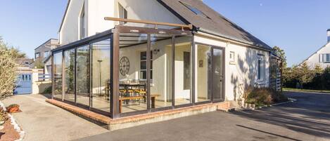 A modern house with a glass conservatory, a dining area, and a visible clock.