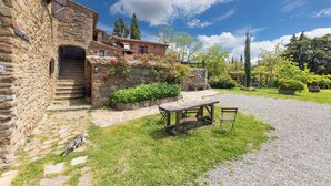 A stone building with a wooden table and chairs in a courtyard.