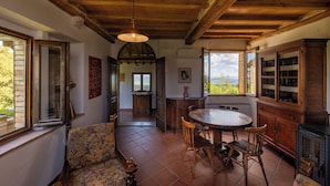 A rustic dining area with a wooden table and chairs, a sofa, and a cabinet.