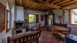 A rustic interior with a fireplace, wooden furniture, and a large window offering a view.