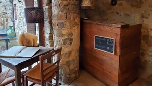 A rustic room with a stone wall, a wooden reception desk, and a table with chairs.