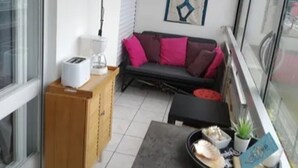 Un petit salon comprenant un canapé, une table basse, une petite table avec une plante et une lampe fixée au mur.