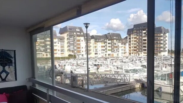 Un balcon donnant sur un port de plaisance et des immeubles d’habitation.