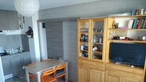 Un espace de vie compact comprenant une cuisine, un coin repas et un meuble pour les appareils multimédias.