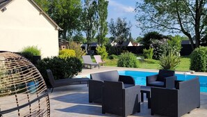 Un área junto a la piscina con mobiliario de mimbre y una piscina.