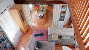 Una habitación acogedora con techo de madera, un conjunto de sofás, una mesita y una estantería.