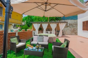 An outdoor patio with wicker furniture, a covered seating area, and a table with drinks. - [MAISON TUSCANY] ★ ★ ★ ★ ★ 20 minutes from Forte dei Marmi | Netflix and Comfort (Carrara)