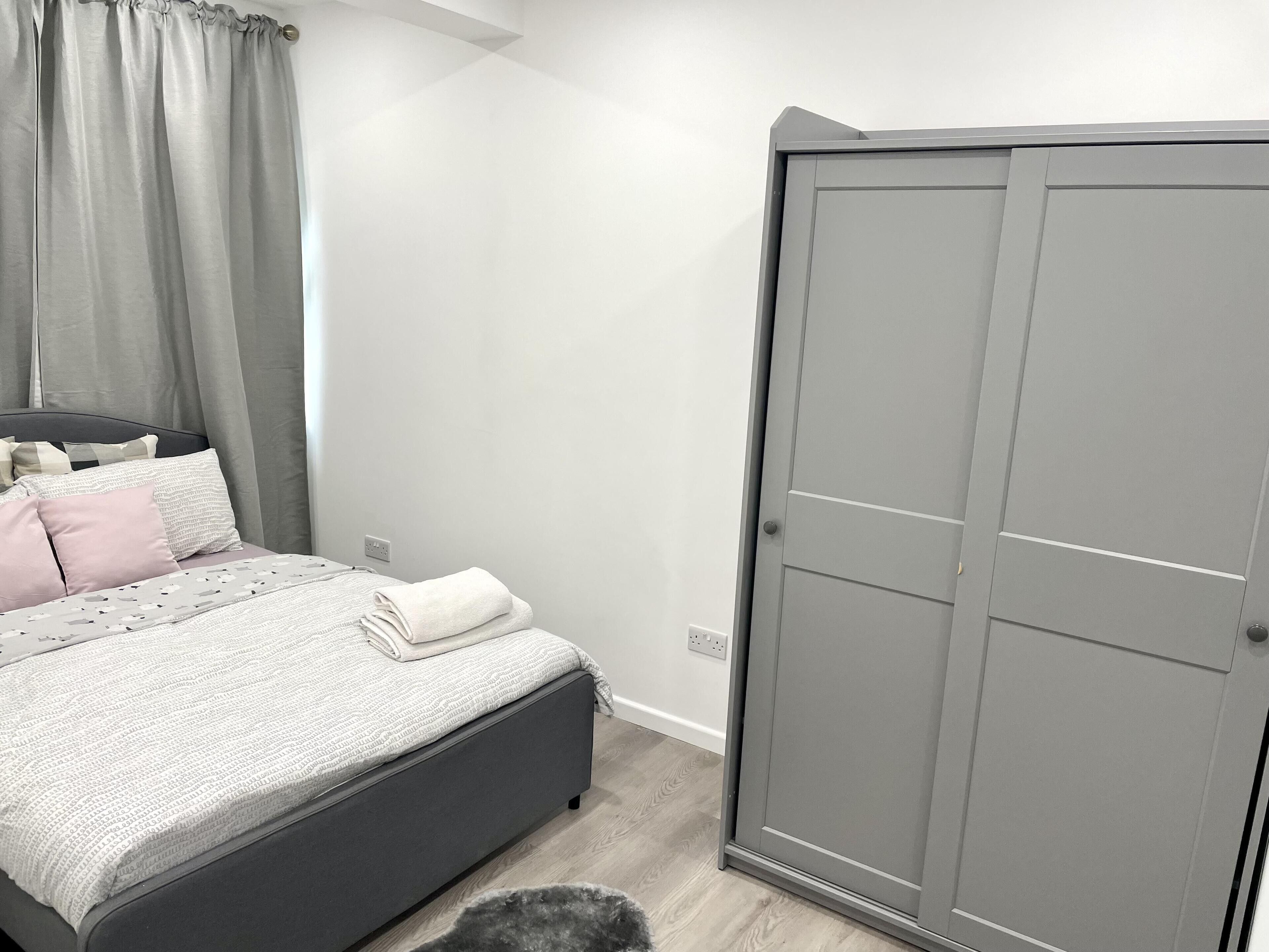 A bedroom with a bed, a wardrobe, and a small rug.