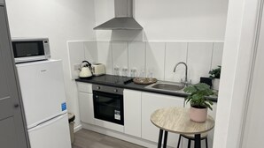 A compact kitchen with a microwave, toaster, sink, and a small dining area with stools.