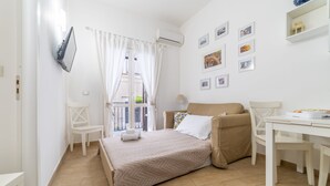 A bedroom with a bed, a chair, a table, and a window with curtains. - Cassari Cottage (Palermo)