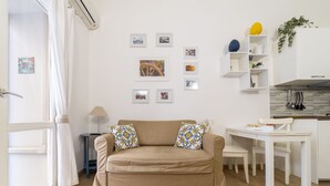 A living room with a beige sofa, a dining table, and a kitchen area. - Cassari Cottage (Palermo)