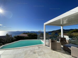 A poolside area with a clear view of the sea and hills. - Modern villa with pool and air conditioning (Cavalaire-sur-Mer)